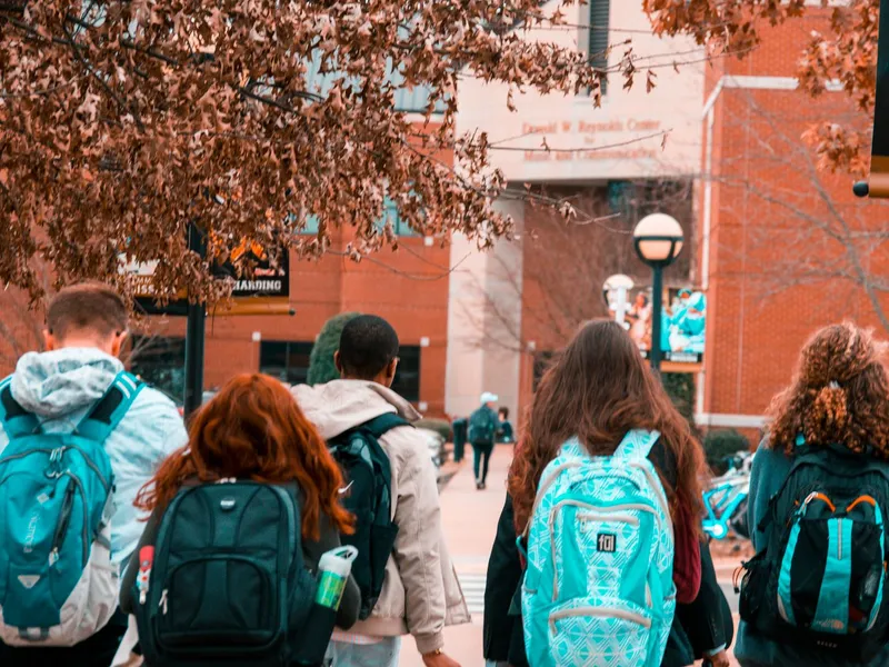 Group of college students with backpacks walking together outdoors on a campus