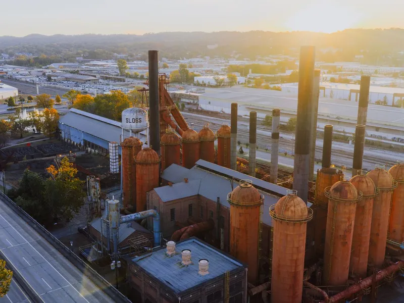 Aerial view of the historic Sloss Furnaces in Birmingham, Alabama, with rust-colored blast furnace stoves at sunset