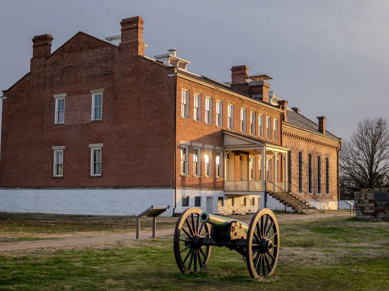 Historic brick building and a Civil War era cannon on the lawn at Fort Smith National Historic Site in Arkansas
