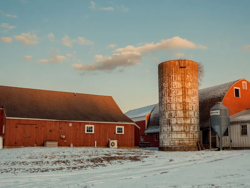 Red barns and a silo on a snowy Connecticut farm at sunset, a historic rural landscape