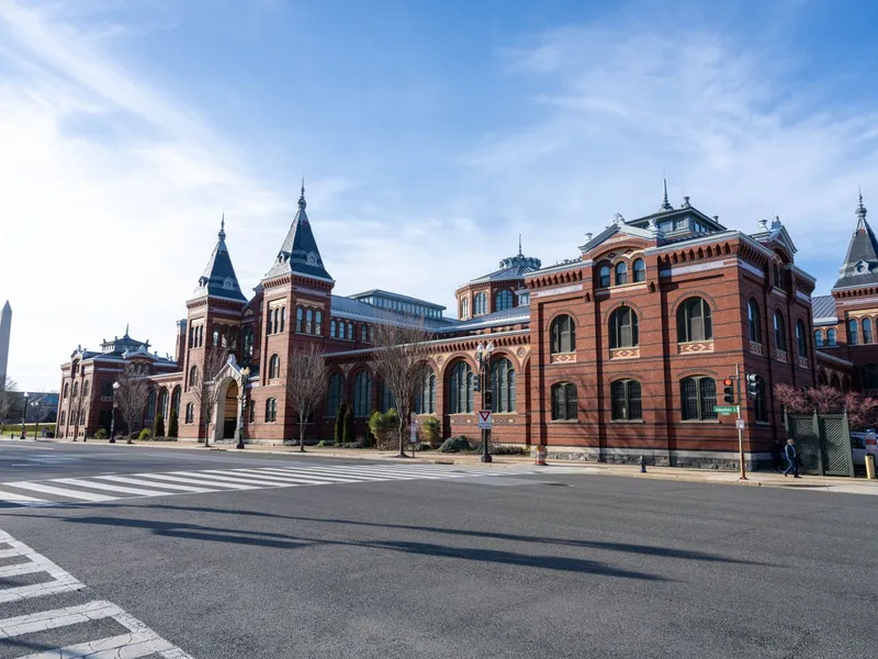 Red brick Smithsonian museum building with towers and the Washington Monument in the distance in Washington, DC