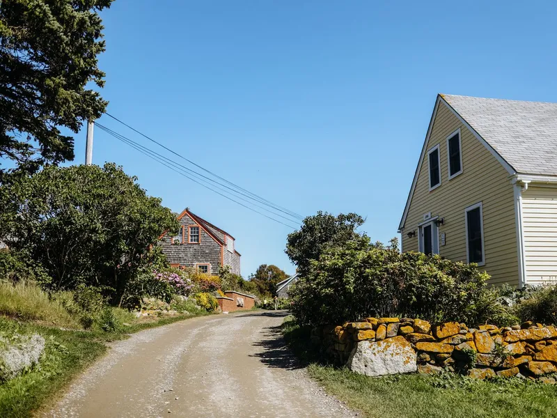 Gravel road lined with shingled New England homes and stone walls in the village on Monhegan Island, Maine