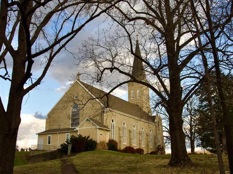 Historic stone church of St. Martin's in Starkenburg, Missouri, on a hillside framed by bare autumn trees
