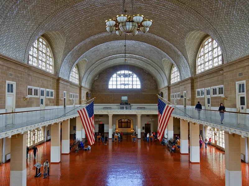Vaulted tile ceiling, arched windows and American flags above the Great Hall at Ellis Island in New York