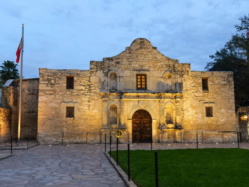 The historic Alamo mission in San Antonio, Texas, with its limestone facade lit at dusk