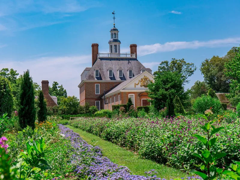 Brick Governor's Palace with cupola behind flowering gardens at Colonial Williamsburg in Virginia