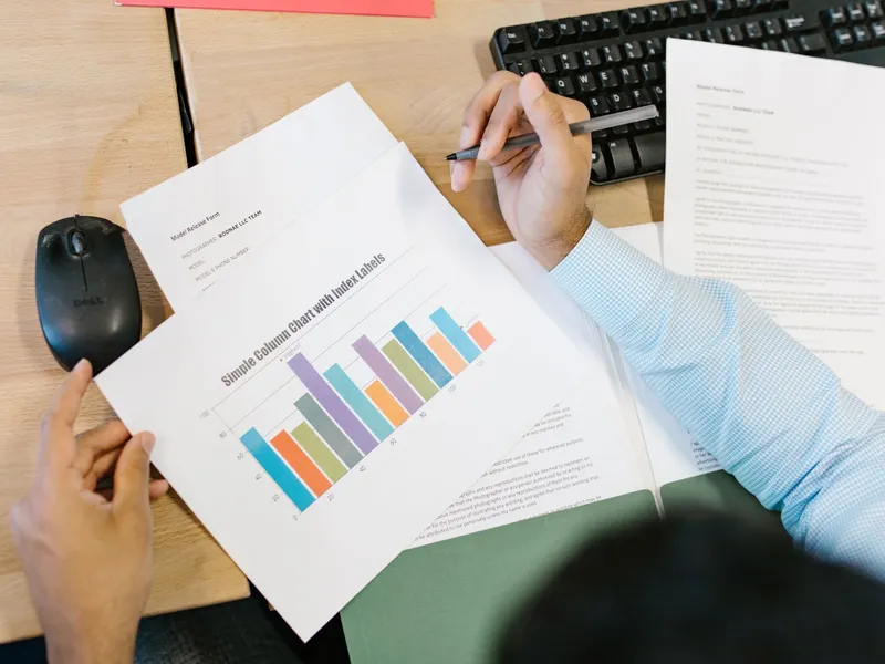 Analyst reviewing a printed bar chart and report with a keyboard on the desk