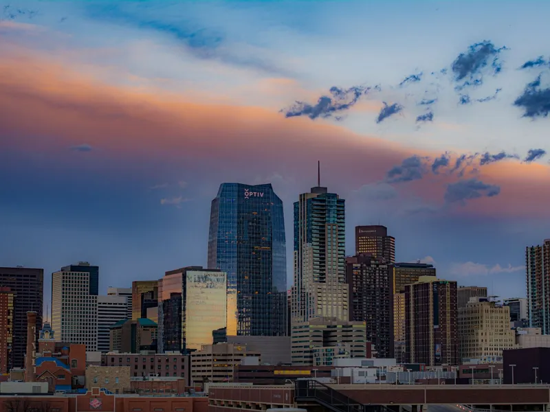 Downtown Denver skyscrapers under a colorful sunset sky