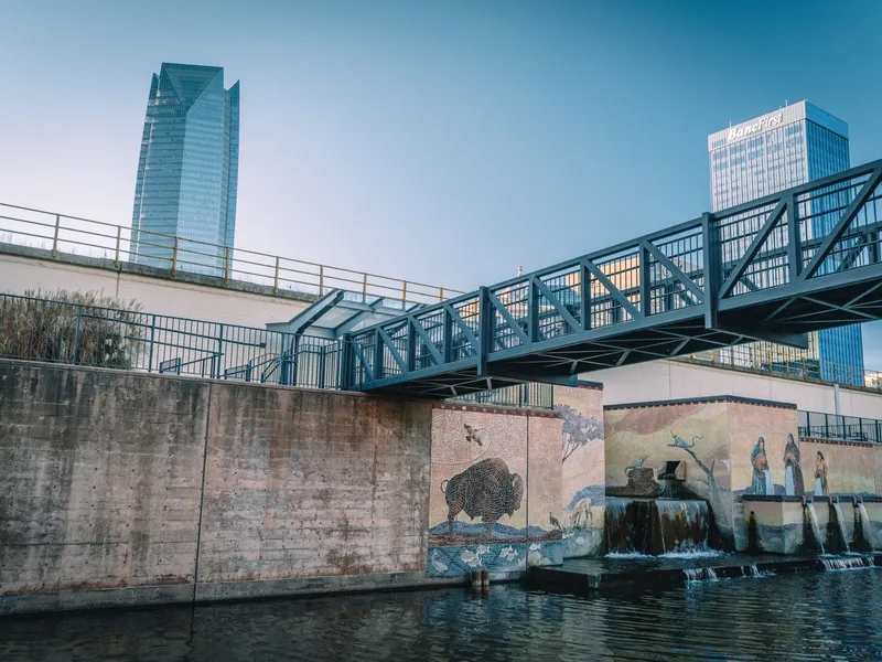 Oklahoma City canal with a footbridge, murals and downtown towers