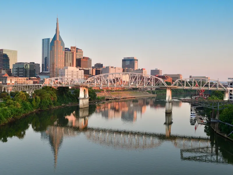 Nashville skyline and pedestrian bridge reflected in the Cumberland River at sunrise