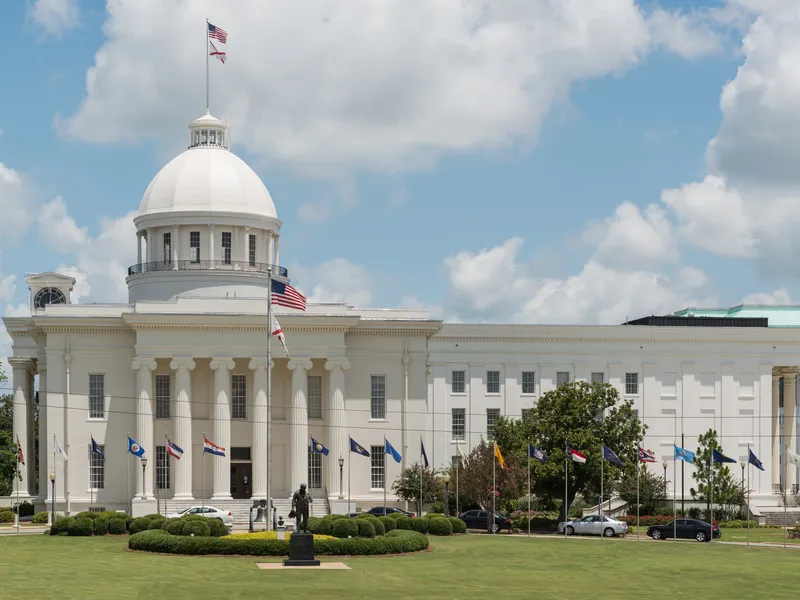 Alabama State Capitol in Montgomery, a white neoclassical building with a dome, columns and a ring of state flags