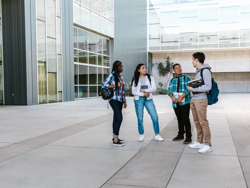 Diverse group of students chatting outside a modern college building