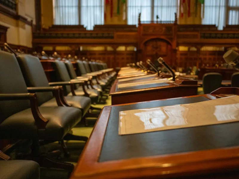 Empty legislative chamber with rows of desks and microphones where policy and government work happens