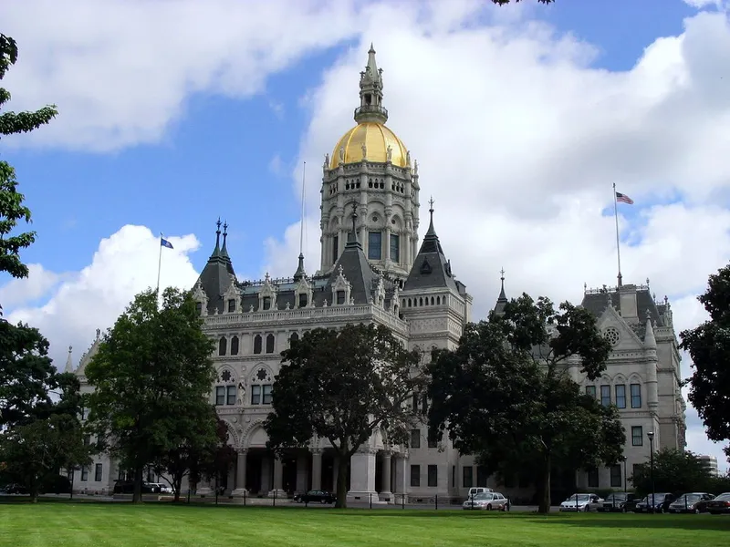 Gold-domed Connecticut State Capitol in Hartford behind a green lawn and trees