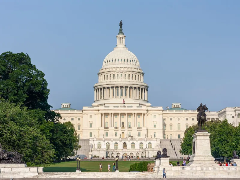United States Capitol dome and facade seen across a green lawn on a clear day in Washington, DC