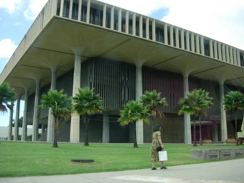 Hawaii State Capitol in Honolulu with its open columned design, palm trees and lawn