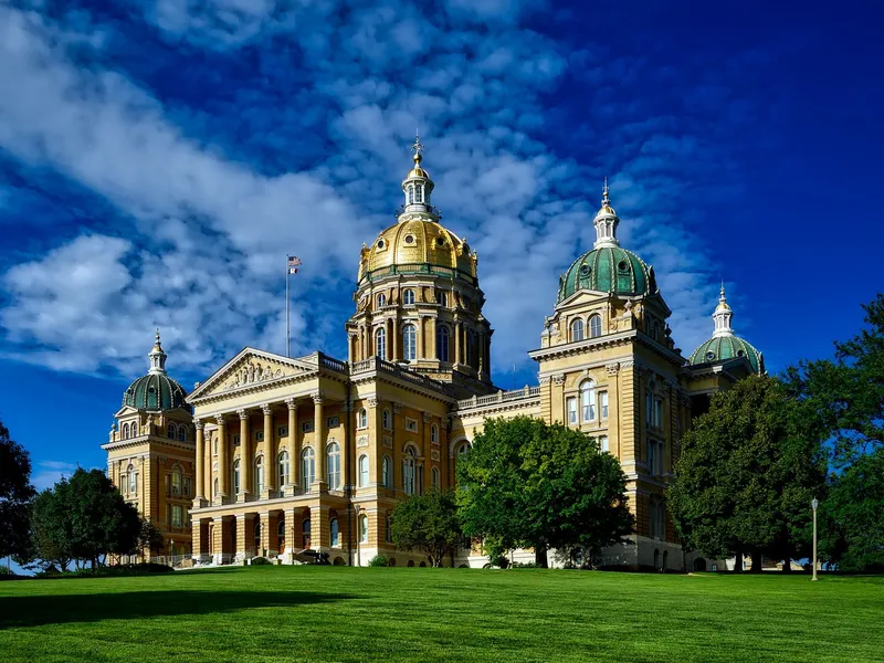 Iowa State Capitol with its golden dome and green lawn on a clear sunny day