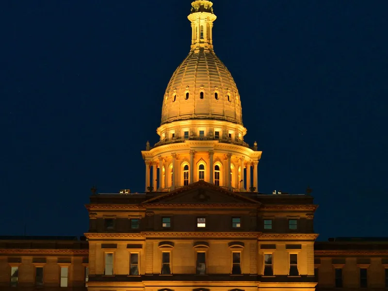 Michigan State Capitol dome lit in gold against the night sky in Lansing