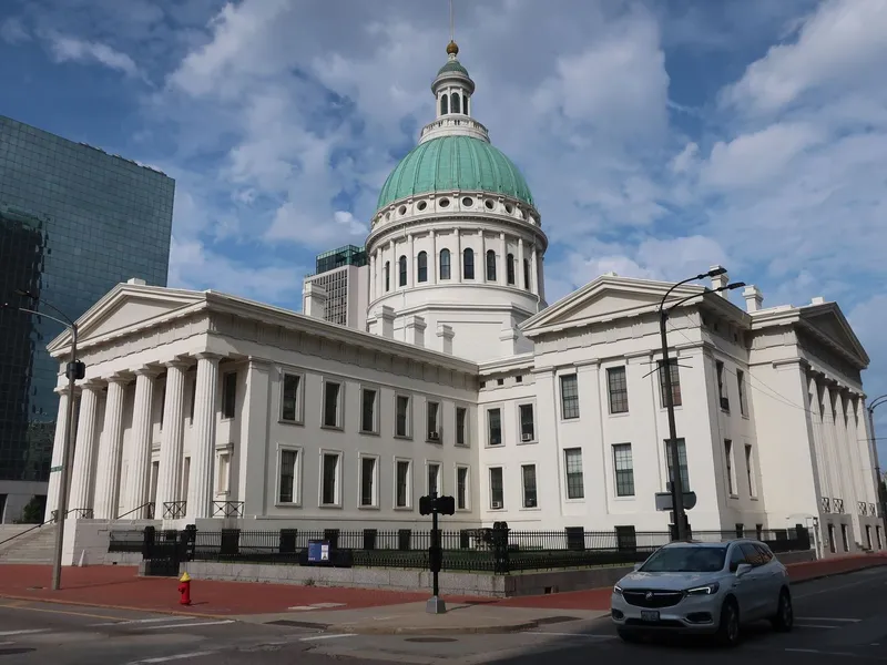 Old Courthouse in St. Louis with its green copper dome and white neoclassical columns under a cloudy sky