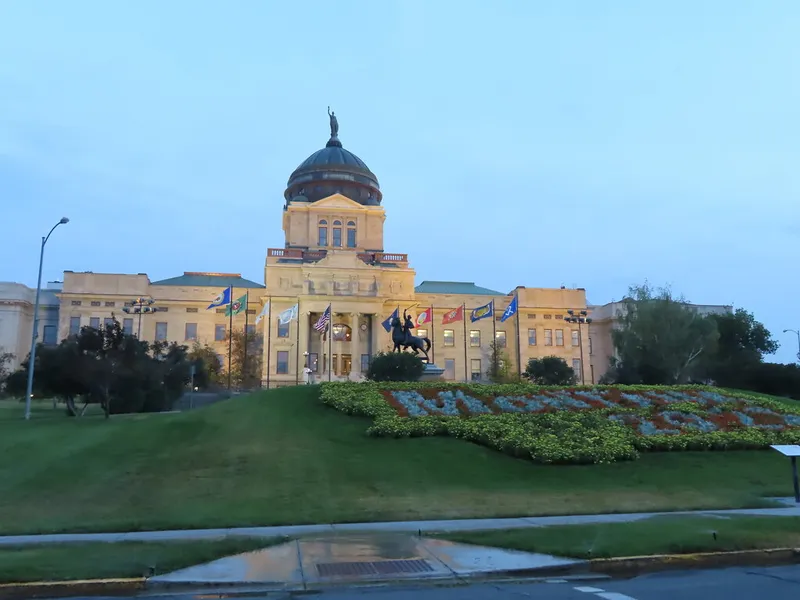 Montana State Capitol in Helena with its copper dome above a landscaped lawn and flags