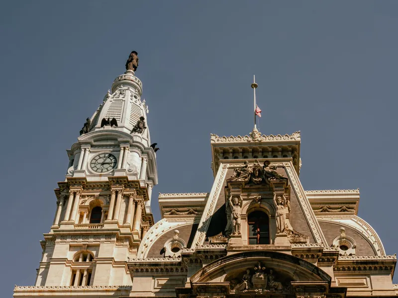 Philadelphia City Hall clock tower and ornate roofline against a clear sky