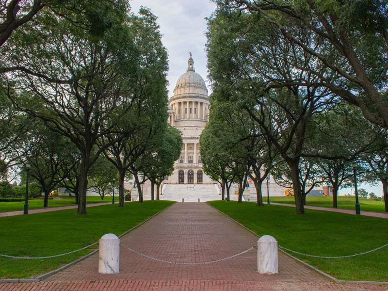 Rhode Island State House at the end of a brick path lined with green trees