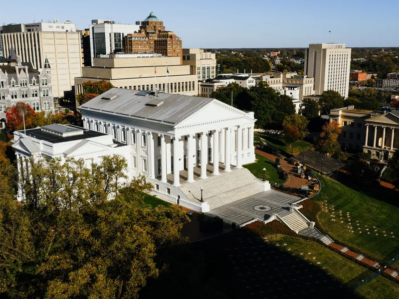 Aerial view of the Virginia State Capitol in Richmond with its white columns, surrounded by autumn trees