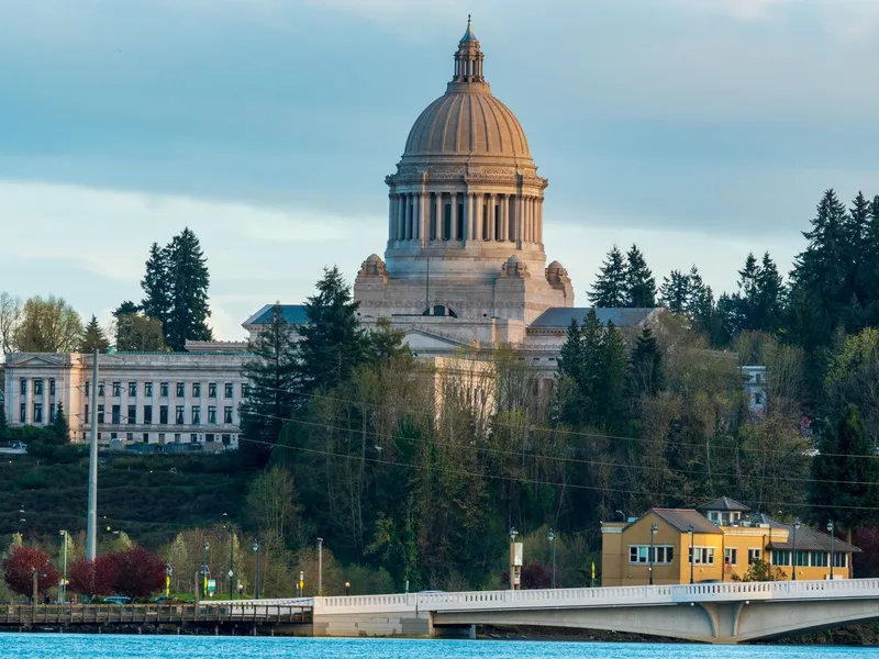 Domed Washington State Capitol in Olympia rising above evergreen trees and the waterfront