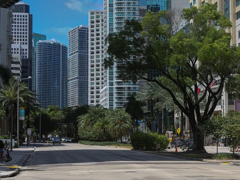 Downtown Miami street lined with palm trees and tall glass skyscrapers on a sunny day
