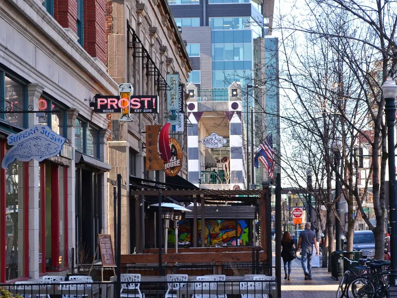Pedestrians walking along a downtown Boise sidewalk lined with restaurants, shops and bicycles