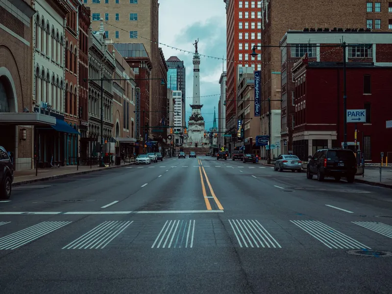 Downtown city street lined with brick buildings, with a tall monument at the far end