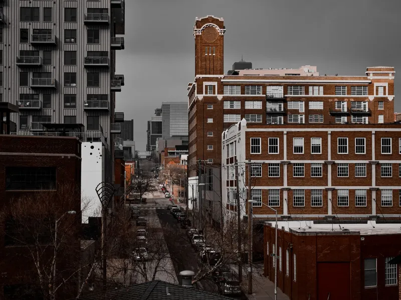 Downtown Kansas City street lined with historic brick buildings and apartment towers on an overcast day