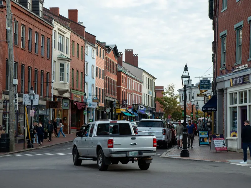 Pedestrians and traffic on a brick-lined downtown street with shops in Portsmouth, New Hampshire