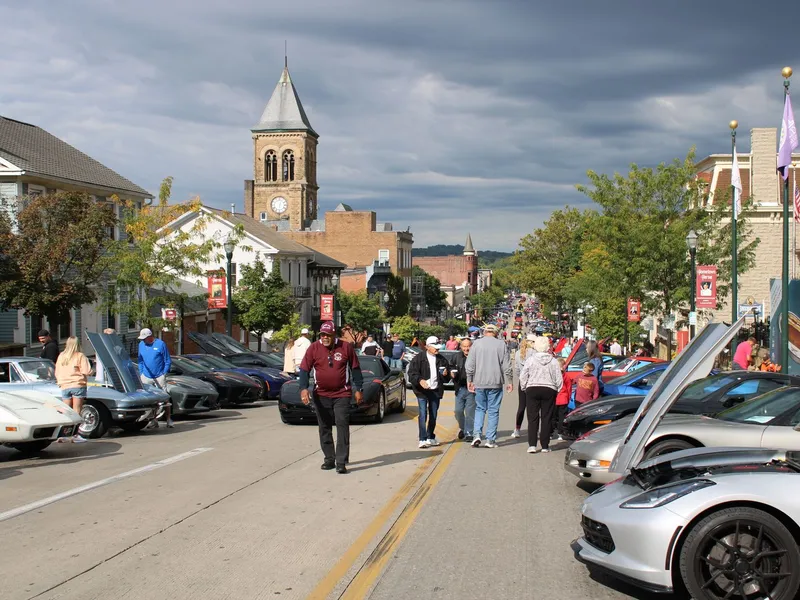 Crowds walking a small-town main street lined with classic cars at a car show in Lancaster, Ohio