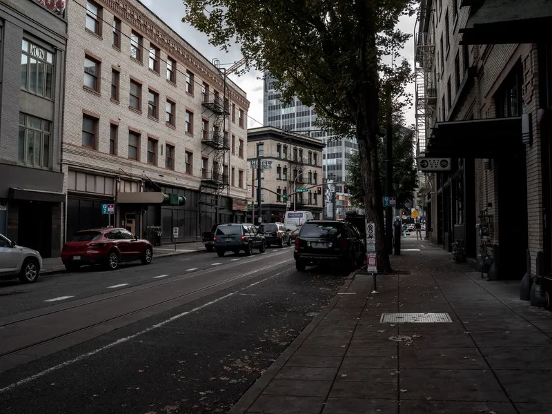 Brick buildings, parked cars and a tree-lined sidewalk on a downtown street in Portland, Oregon