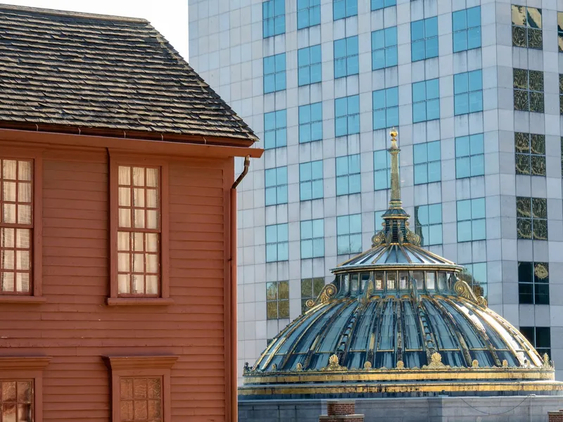 Providence, Rhode Island, where a colonial wooden building stands beside a modern glass tower and historic dome