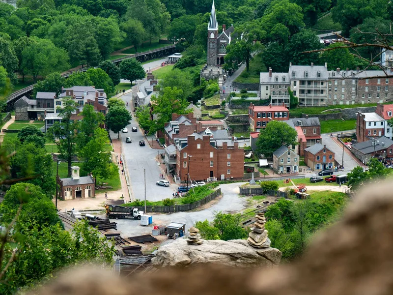 Aerial view of historic brick buildings, a church and a street in Harpers Ferry surrounded by green trees