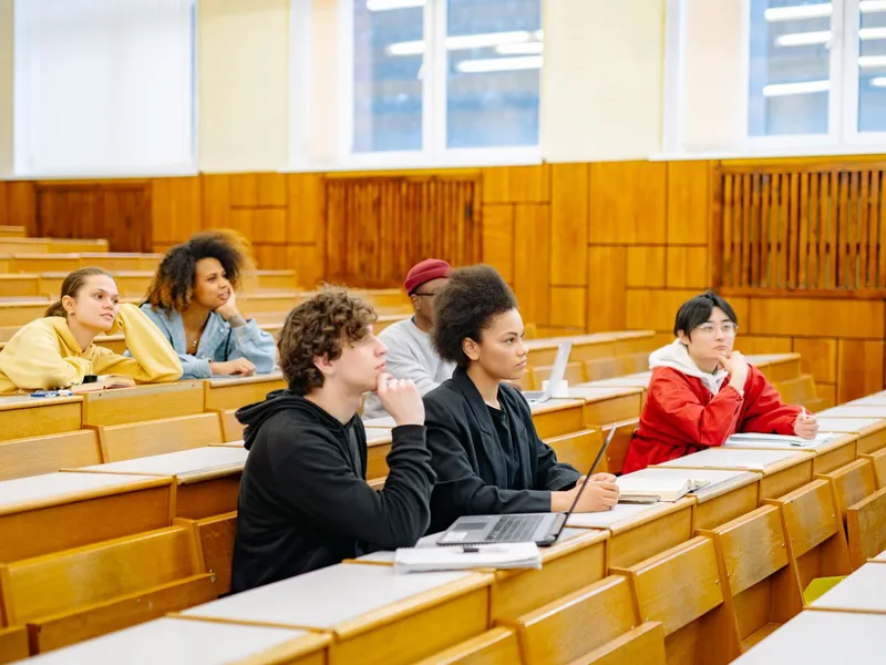 Students of various backgrounds listening attentively in a tiered university lecture hall