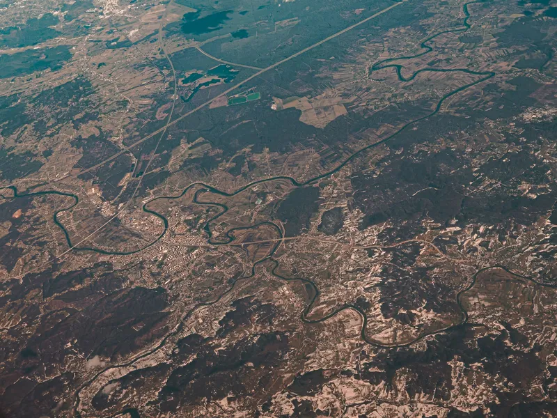 Aerial view of a river winding through plains and forest land