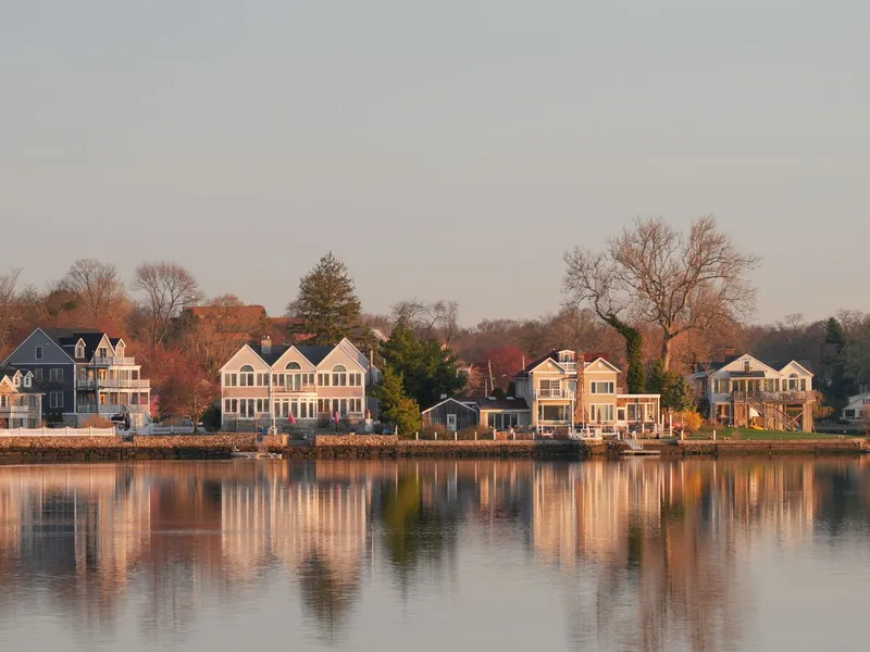 Waterfront homes reflected in calm water at sunrise on the Connecticut shoreline in Stamford