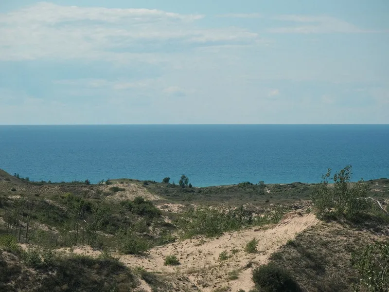 Sand dunes and grassy bluffs overlooking the blue water of Lake Michigan