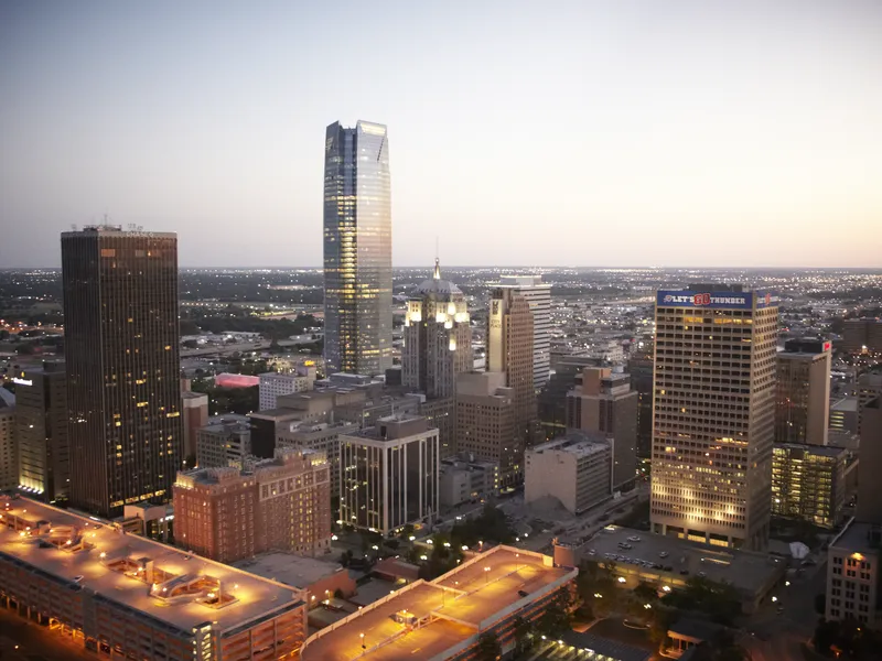 Downtown Oklahoma City skyline at twilight with glass towers and lit parking structures