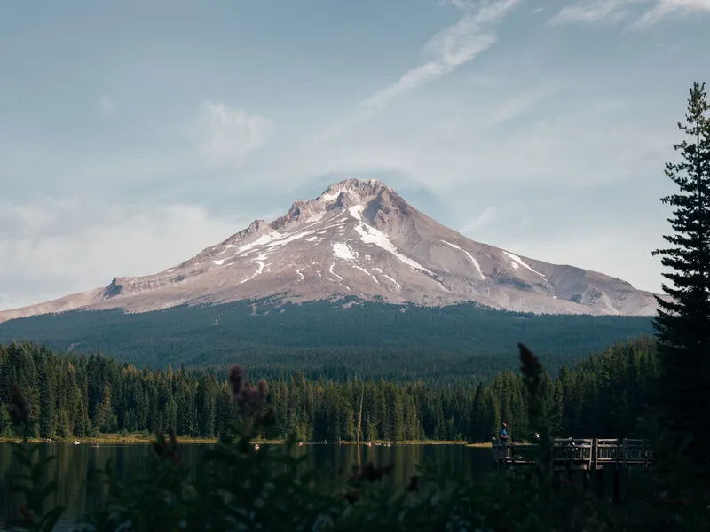 Mount Hood rising above evergreen forest and a calm lake in Oregon