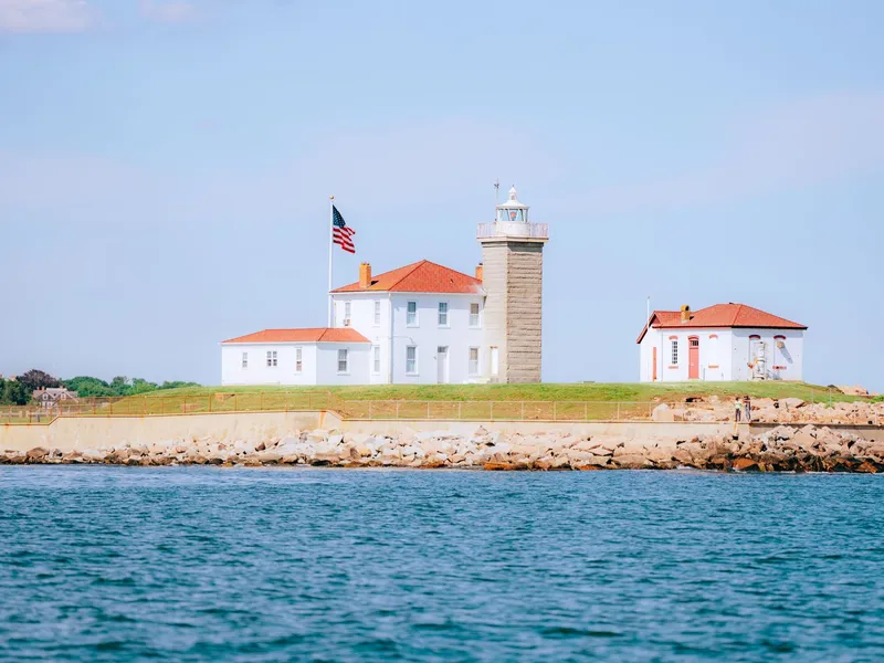 Watch Hill Lighthouse and keeper's houses on the Rhode Island shoreline across blue water