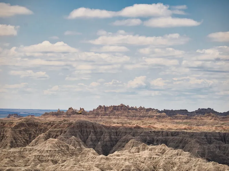 Layered eroded rock formations of the Badlands under a wide cloudy sky
