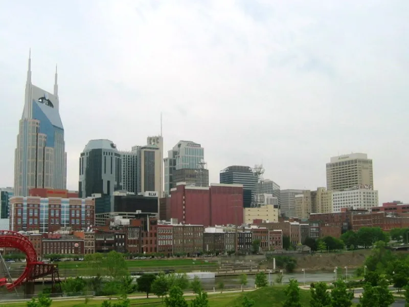 Nashville skyline with downtown towers rising above the Cumberland River riverfront and a red sculpture