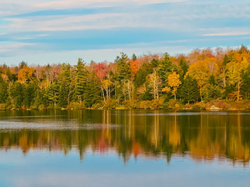 Vermont autumn foliage reflected in a calm lake under a blue sky