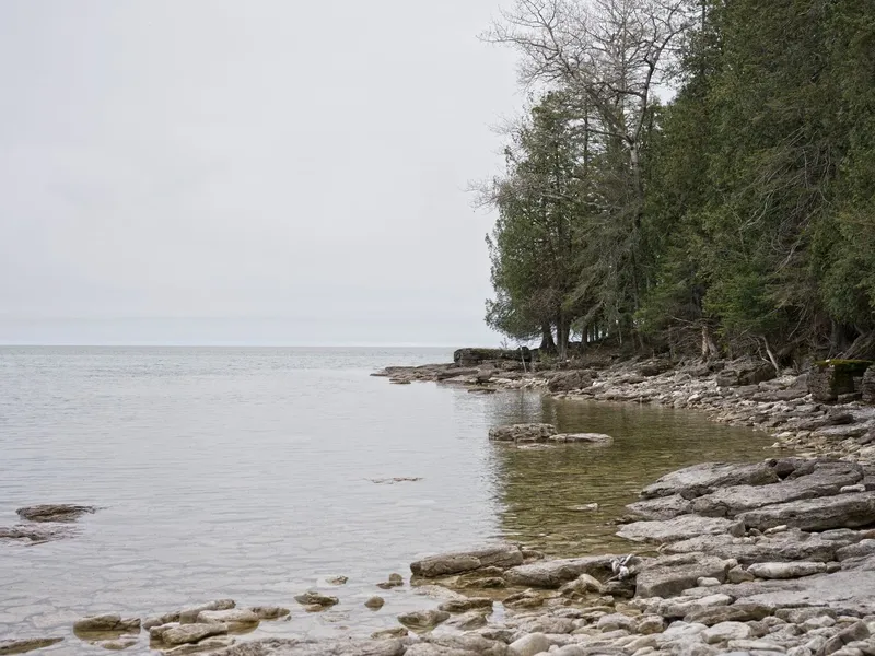 Rocky Lake Michigan shoreline with calm water and evergreen trees in Wisconsin